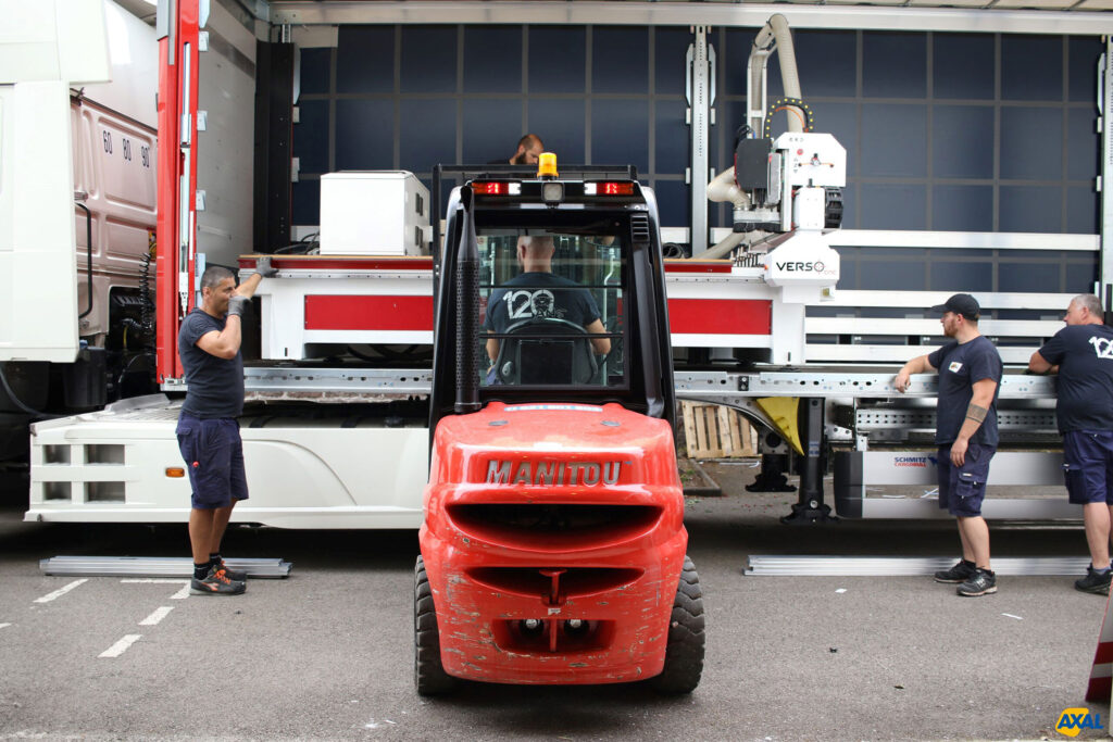Cariste et techniciens Axal effectuant le transfert d'équipements lourds pour une imprimerie