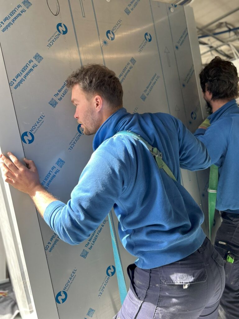 Techniciens manutentionnaire transportant du matériel lourd à l'aide de sangles